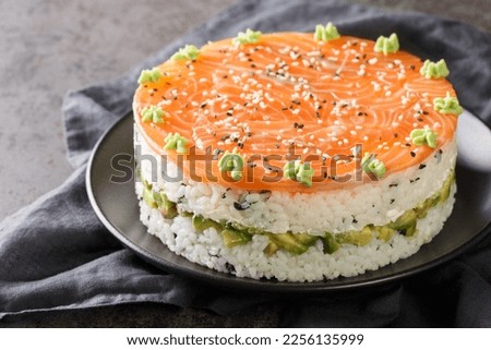 Sushi cake with a salmon, rice, avocado and philadelphia cheese closeup on the plate on the table. Horizontal
