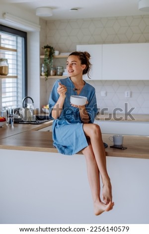 Young woman having muesli for breakfast in her kitchen, morning routine and healthy lifestyle concept. Royalty-Free Stock Photo #2256140579