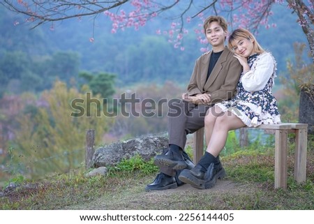 Young couple Teenage happy in the fresh beautiful Cherry pink blossom Sakura flowers full bloom in the park with a joyful holiday vacation. Valentine's Day lover of young fashion nature.