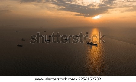 Seascape and silhouette container ship floating in sea and over the sunset background, aerial view photography from drone.