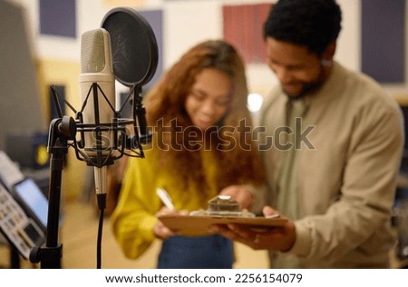 People, clipboard and sign up for podcast, microphone or karaoke in registration at studio event. Man helping woman write time and schedule for live streaming, audition or castings on condenser mic