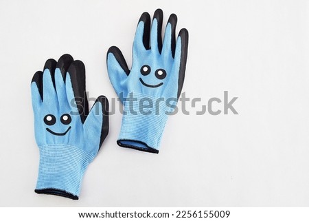 Blue, work gloves with a smiley on a white background.  Gardening accessories.  Free space for text.