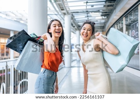 Portrait of Asian attractive two girl shopping indoor in shopping mall. Beautiful woman holding shopping bags then walking alone with happiness, enjoy purchasing in department store and look at camera Royalty-Free Stock Photo #2256161107