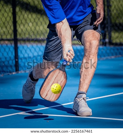 Pickleball player his a low volley using a forehand shot Royalty-Free Stock Photo #2256167461