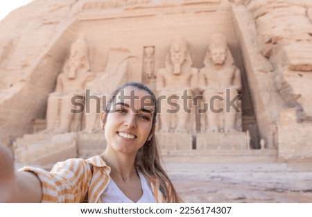 Horizontal selfie viewof young beautiful smiling tourist woman with Abu simbel temple in the background