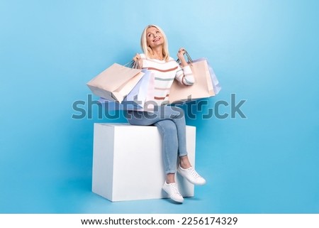 Photo of gorgeous lady sitting looking empty space cool proposition stylish clothes low prices isolated on blue color background