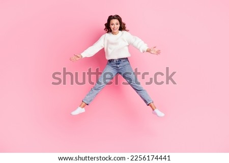 Full length photo of adorable excited lady wear white sweater jumping high smiling isolated pink color background