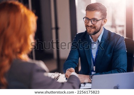 Happy bank manager shaking hands with a client after successful agreement in the office.  Royalty-Free Stock Photo #2256175823