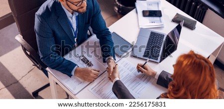 Happy bank manager shaking hands with a client after successful agreement in the office.  Royalty-Free Stock Photo #2256175831