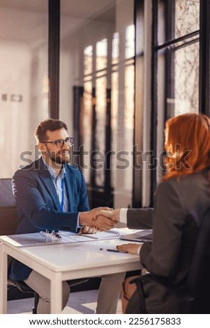 Happy bank manager shaking hands with a client after successful agreement in the office.  Royalty-Free Stock Photo #2256175833