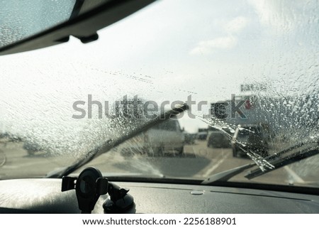 Close-up of wiper cleaning windshield with fluid Royalty-Free Stock Photo #2256188901