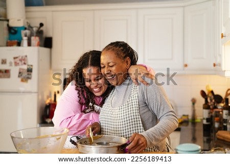 Happy African mother and daughter preparing a homemade dessert Royalty-Free Stock Photo #2256189413