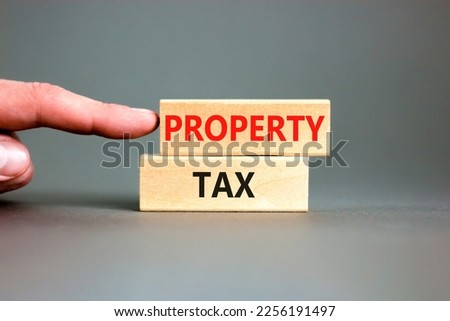Property tax symbol. Concept words Property tax on wooden blocks. Beautiful grey table grey background. Businessman hand. Business and property tax concept. Copy space.