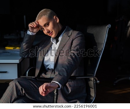 Business woman with short hair sits in the office and holds a digital tablet with a stylus pen