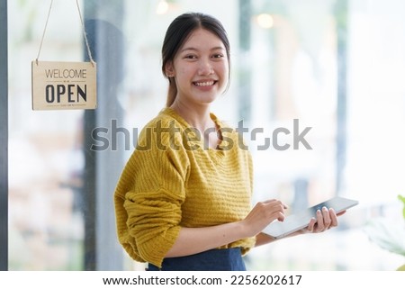Beautiful female manager in restaurant with tablet. Woman coffee shop owner with open sign. Small business concept