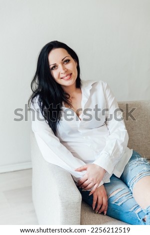 woman in a free style sits in a room on a sofa