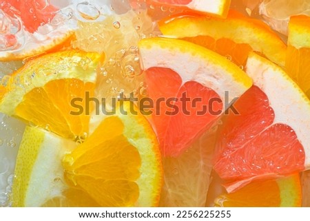 Fresh slices of grapefruit, orange fruit and honey pomelo on white background. Pieces of grapefruit, orange fruit and honey pomelo in sparkling water on white background, close-up. Horizontal image. Royalty-Free Stock Photo #2256225255