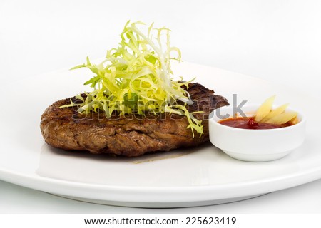Succulent thick juicy portions of fried fillet steak, served with a tomato sauce on a white plate