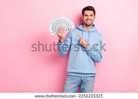 Photo of sweet cute man wear blue hoodie pointing cash fan empty space isolated pink color background