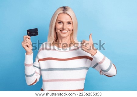 Photo of cute confident woman dressed striped sweater rising bank thumb up isolated blue color background