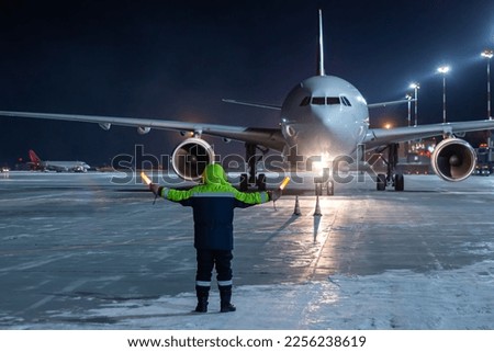 Airliner marshalling at the aiport apron at winter night. Passenger aircraft meeting Royalty-Free Stock Photo #2256238619