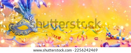 Carnival Party - Venetian Mask On Yellow Satin With Shiny Streamers On Abstract Defocused Bokeh Lights Royalty-Free Stock Photo #2256242469