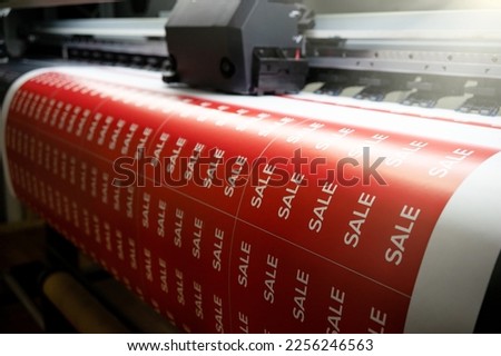 Printing a banner with the inscription sale on the printing press. Large-format printing in production. Stickers are on sale for Black Friday.