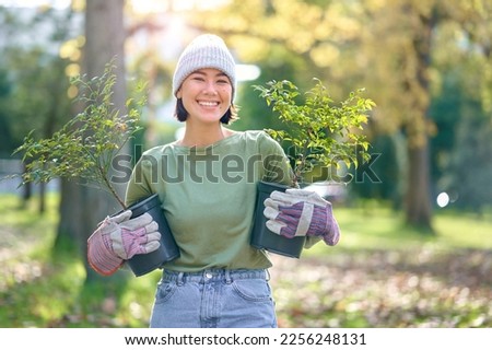Woman portrait, plant and gardening in a park with trees in nature environment, agriculture or garden. Happy volunteer planting for growth, ecology and sustainability for community on Earth day Royalty-Free Stock Photo #2256248131