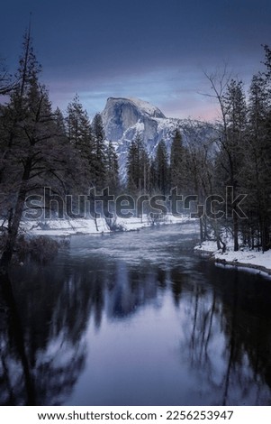 Dark stunning sunset view with water reflections of Half Dome in winter Yosemite National park, picture was taken from the bridge on Merced River in Yosemite valley 