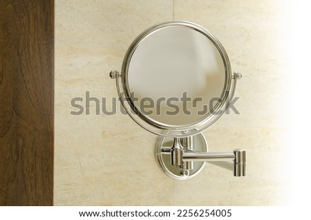 Cosmetic round bathroom mirror with ivory wall tiles and LED lighting. Personal tool for applying makeup, shaving, face care.
