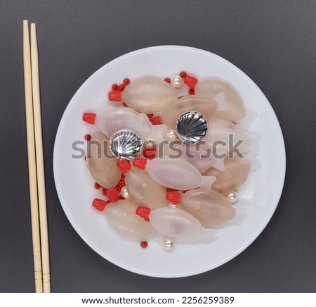 Plastic fish and other plastic and garbage products on a plate. Top view. Plastic disposable container for soy sauce. Plastic in our food. Pollution of the oceans. Zero waste, recycling, reuse.