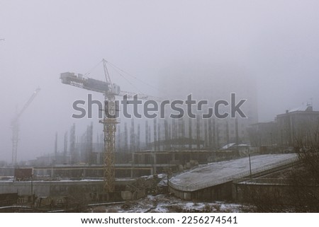 Vintage Style Horizontal photo of a Construction site with Cranes in Misty Snowy Winter