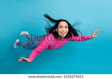 Full length photo of carefree adorable lady wear pink pullover arms wings flying air isolated blue color background Royalty-Free Stock Photo #2256279651