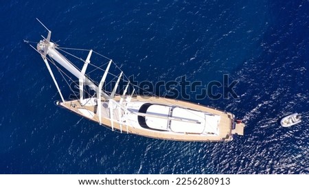 Aerial drone top down photo of beautiful sail boat with wooden deck anchored in deep blue Mediterranean sea