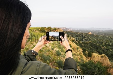 Female persons hands are holding the smartphone and taking photo of beautiful nature landscape on tour around VAshlovani national park. Smartphone photography and using grid mode