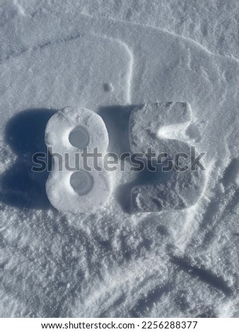 Top view of the number eighty five carved in snow, on the snow. A eight and a five