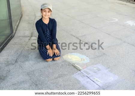 little girl draws on the pavement.