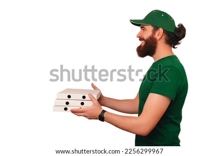 Side view shot of a delivery man wearing green holding three boxes of pizza over white background.