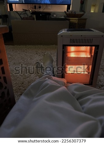 Picture of human legs worming up by the electric heater