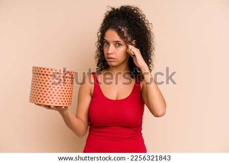 Young african american woman holding a valentines day box gift isolated pointing temple with finger, thinking, focused on a task.