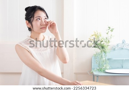 Asian woman touching her eyes Royalty-Free Stock Photo #2256334723