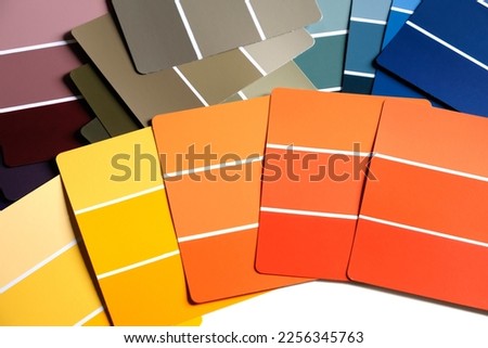 Color sample swatches on a table or desk. Swatches are in various shades of yellows, oranges, purple, blues and greens. Spring or fall color schemes. Interior design color pallet. Creative inspiration