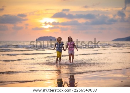 Child playing on ocean beach. Kid jumping in the waves at sunset. Sea vacation for family with kids. Little boy and girl running on exotic island during summer holiday.
