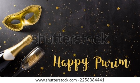 Happy Purim carnival decoration concept made from golden mask, wine, gift box and sparkle star on dark background. (Happy Purim in Hebrew, jewish holiday celebrate)