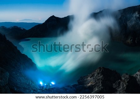 Landscape of Kawah ijen volcano crater with blue flame and acid sulfuric smoke view at dawn morning. Beautiful Landmark of nature adventure for traveler in East Java, Indonesia