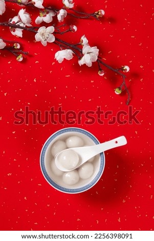 Tang Yuan(sweet dumplings balls) with plum flower in a bowl. traditional cuisine food on red background. Royalty-Free Stock Photo #2256398091