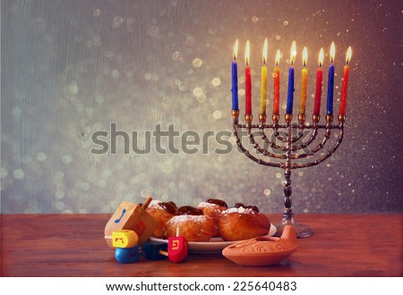 low key of jewish holiday Hanukkah with menorah, doughnuts and wooden dreidels (spinning top). retro filtered image
