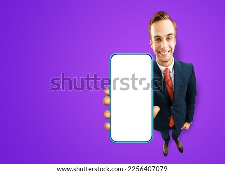 Full body image of businessman in eye glasses, black suit showing cell phone, mobile smartphone, on purple background. Comic cartoon funny businessman in eyeglasses with cellphone. Expert recommending