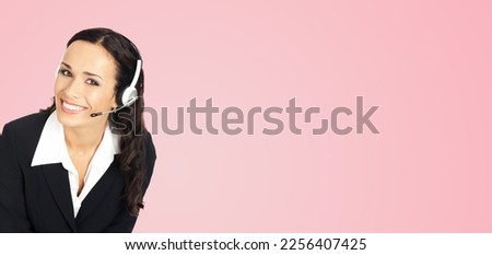 Call center service. Portrait image of female customer support phone sales operator in headset showing something or copy space area for text or slogan, over rose pink background. 