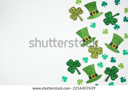 St Patricks Day shamrock and green leprechaun hat side border. Top down view over a white background with copy space.